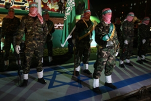 Membros de Ham&aacute;s, esta cuarta feira, sobre a bandeira de Israel