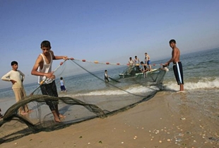 Mozos palestinos preparan unha rede de pesca nunha praia no centro da Faixa de Gaza, este lunes