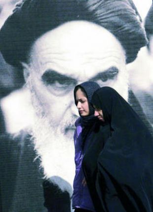 Dúas mulleres pasan por diante dunha imaxe de Khomeini en Teheran