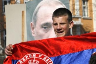 Un cativo serbo-bosnio porta unha bandeira de Serbia e marcha diante dun retrato do presidente ruso, Vladimir Putin